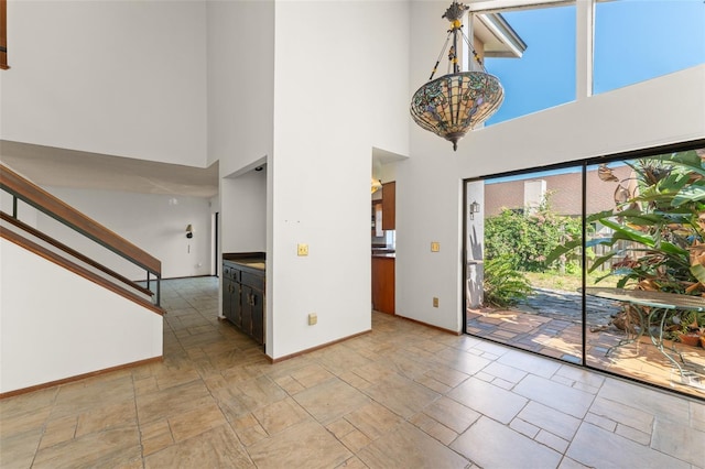 foyer with stairway, a high ceiling, stone finish flooring, and baseboards