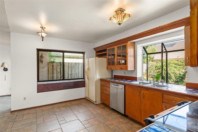 kitchen featuring stainless steel dishwasher, electric stove, a sink, brown cabinets, and white fridge with ice dispenser