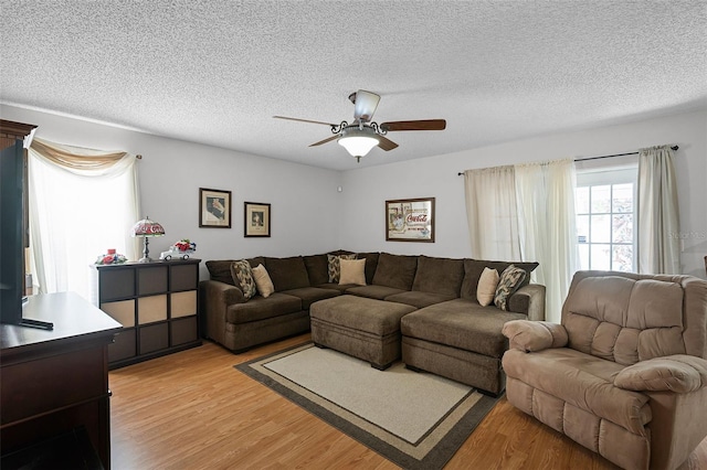 living area with a ceiling fan, light wood finished floors, and a textured ceiling