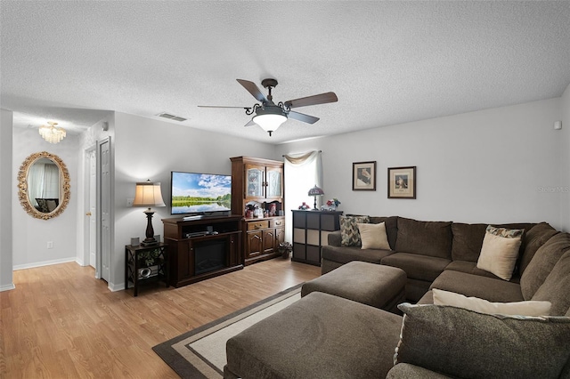 living area with a ceiling fan, light wood-type flooring, a textured ceiling, and visible vents