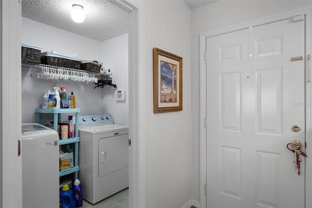 laundry area with baseboards, laundry area, a textured ceiling, and washer and clothes dryer