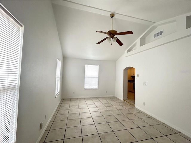 empty room featuring high vaulted ceiling, light tile patterned floors, ceiling fan, arched walkways, and visible vents