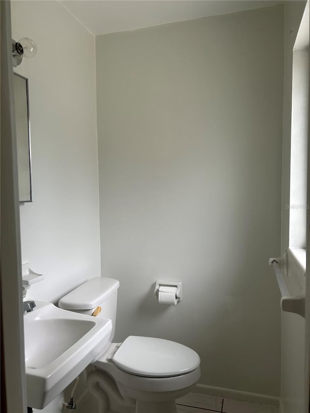 half bathroom with toilet, tile patterned floors, and a sink