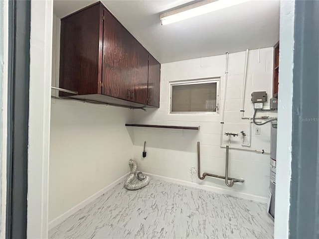 laundry area featuring water heater, baseboards, and cabinet space
