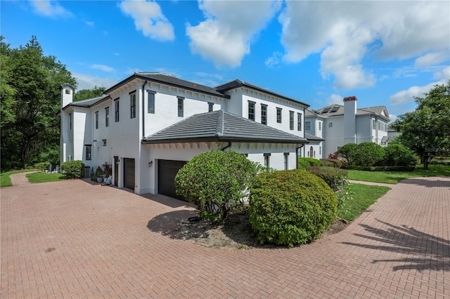 10849 Emerald Chase Dr, Orlando, FL 32836 - view of property exterior featuring a garage, decorative driveway, stucco siding, and a chimney