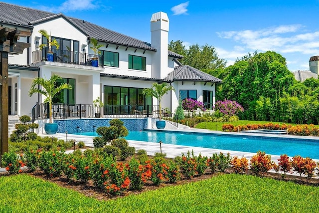 570 Manor Rd, Maitland, FL 32751 - rear view of property featuring a balcony, a chimney, an outdoor pool, a tiled roof, and stucco siding
