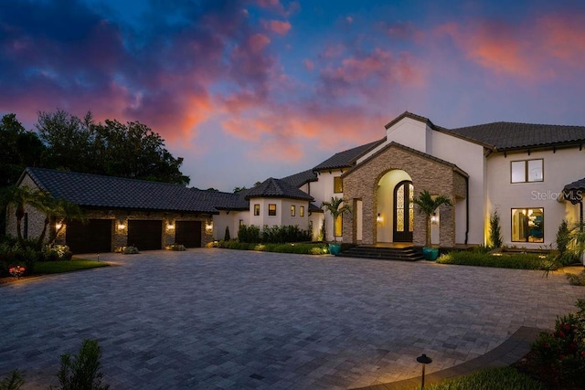 570 Manor Rd, Maitland, FL 32751 - view of front of property featuring a tile roof, decorative driveway, stone siding, a garage, and stucco siding
