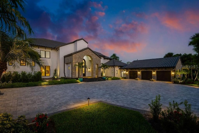 570 Manor Rd, Maitland, FL 32751 - view of front facade featuring a tile roof, stone siding, an attached garage, stucco siding, and decorative driveway