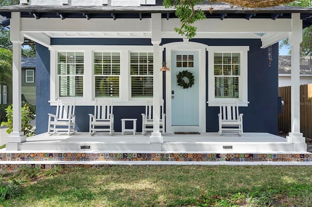 property entrance with covered porch and stucco siding