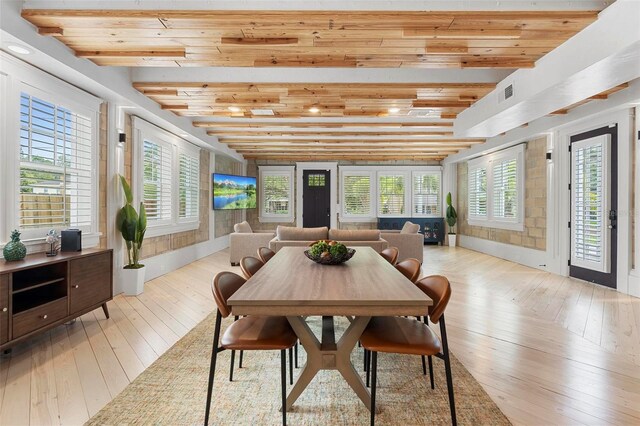 dining space featuring hardwood / wood-style flooring, beamed ceiling, and plenty of natural light