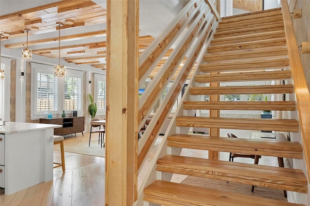 stairs featuring wood-type flooring and beamed ceiling