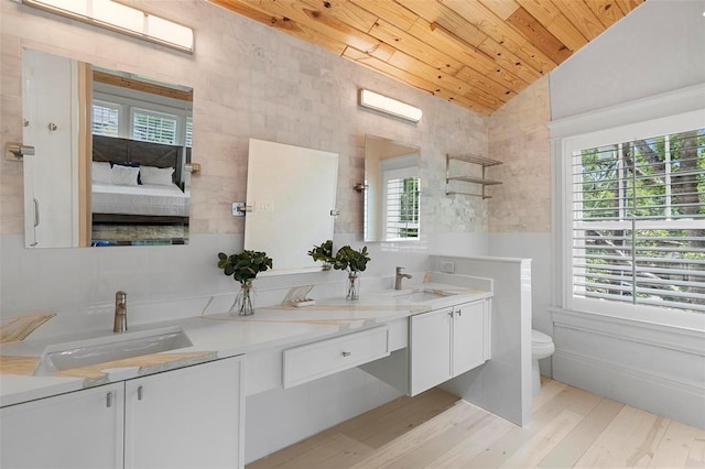 ensuite bathroom featuring vaulted ceiling, wooden ceiling, healthy amount of natural light, wood finished floors, and double vanity