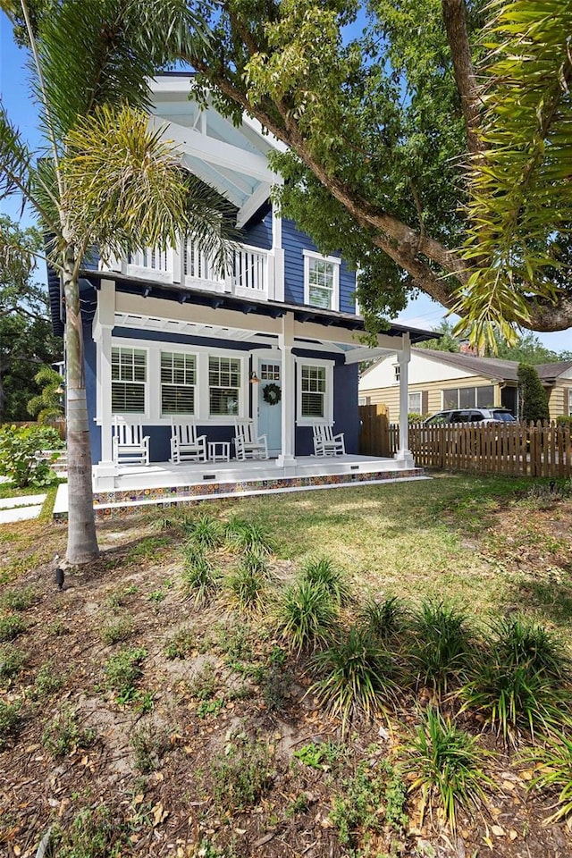 view of front of house with fence and a balcony