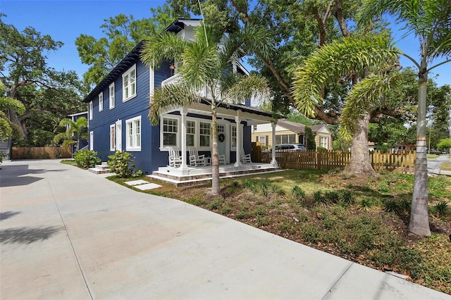 view of front of property with fence, covered porch, and driveway