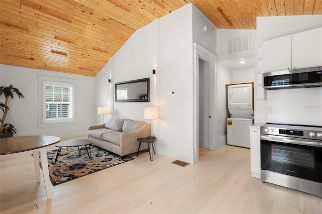 living room with wood ceiling, estacked washer and dryer, high vaulted ceiling, light wood-type flooring, and baseboards