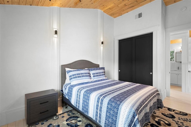 bedroom featuring wood ceiling, wood finished floors, and a sink