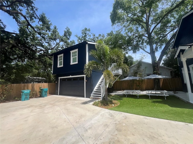 view of side of home featuring stairway, concrete driveway, and an attached garage