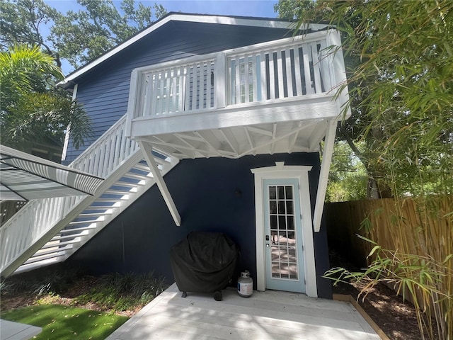 back of house featuring fence, stairs, a balcony, and a wooden deck
