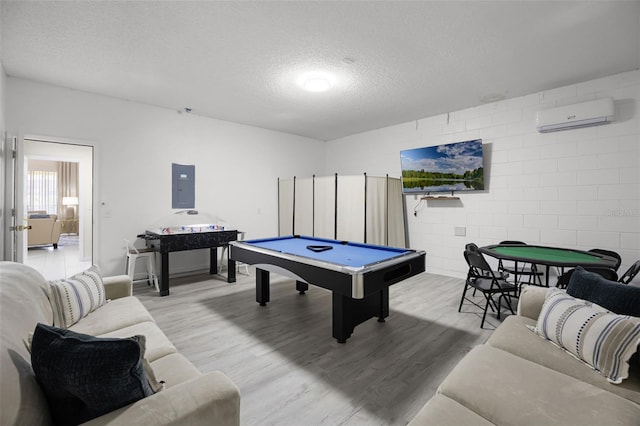 game room with billiards, a wall unit AC, electric panel, a textured ceiling, and wood finished floors