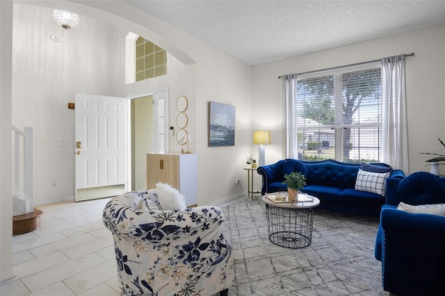 living room featuring baseboards, arched walkways, a textured ceiling, and stairs