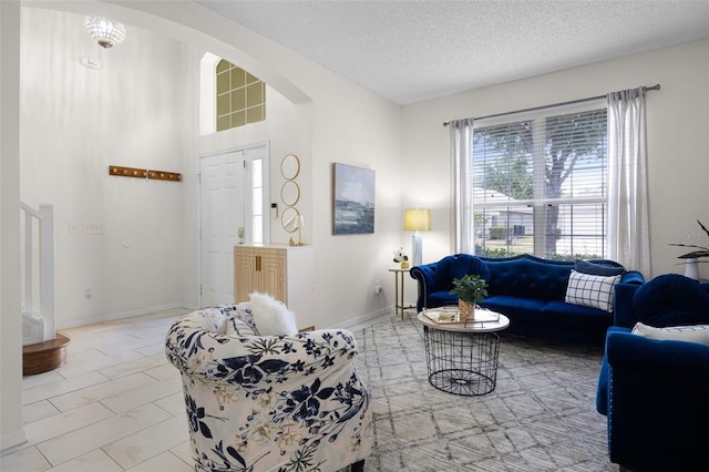 living room featuring arched walkways, a textured ceiling, and baseboards