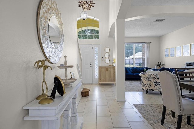 entryway with arched walkways, a textured ceiling, and visible vents