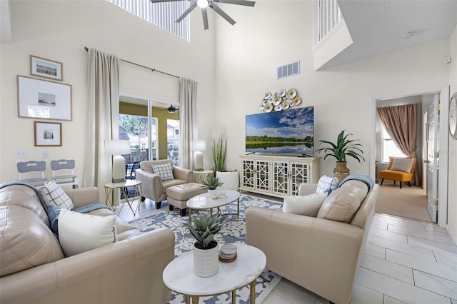 living area featuring a towering ceiling, a ceiling fan, and visible vents