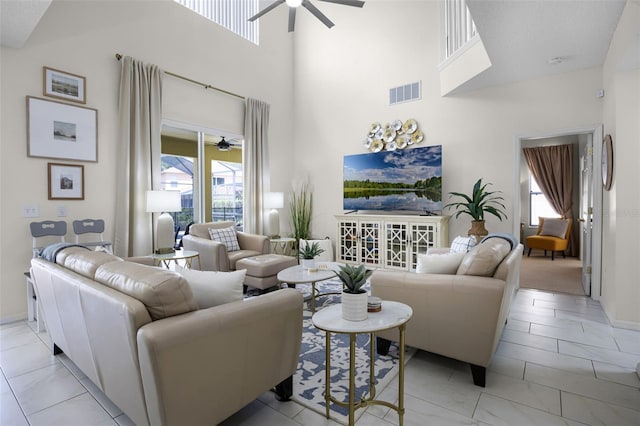 living room with a high ceiling, marble finish floor, a ceiling fan, baseboards, and visible vents