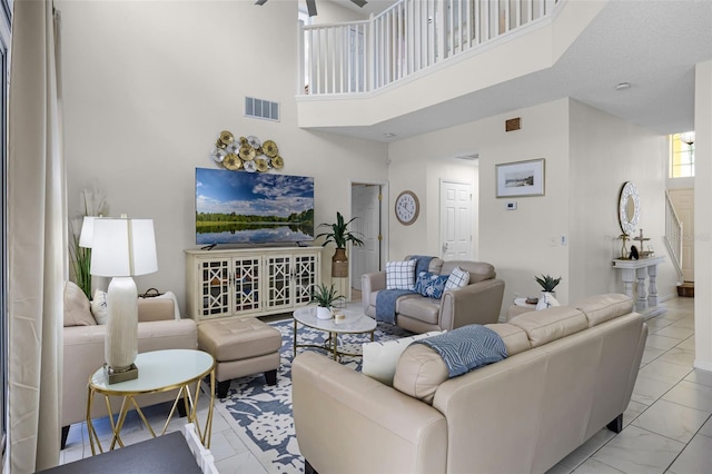 living area with visible vents, marble finish floor, ceiling fan, and a high ceiling
