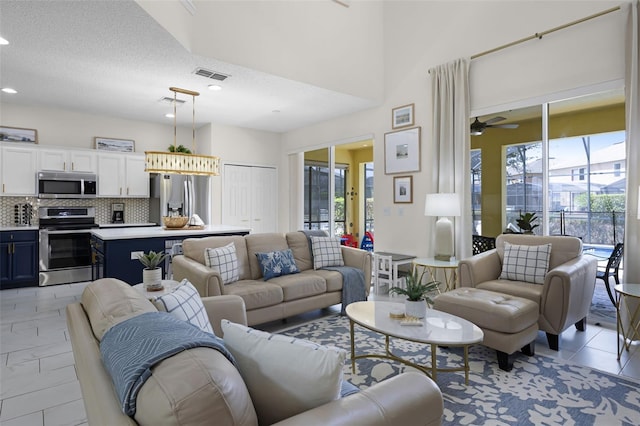 living room featuring ceiling fan, recessed lighting, a textured ceiling, and visible vents