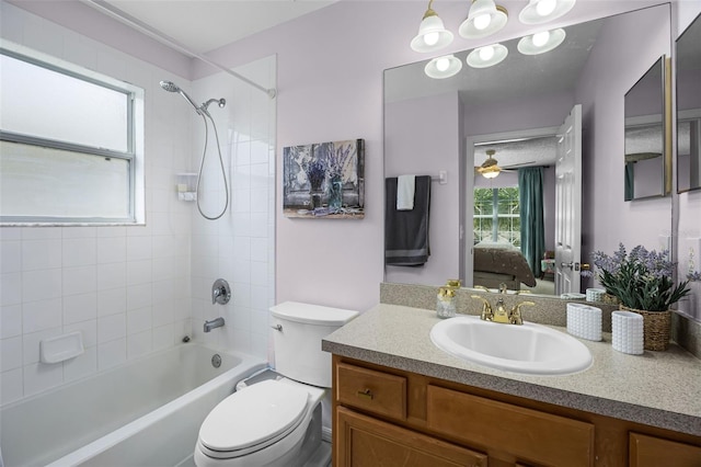 ensuite bathroom featuring a ceiling fan, vanity, toilet, washtub / shower combination, and ensuite bath