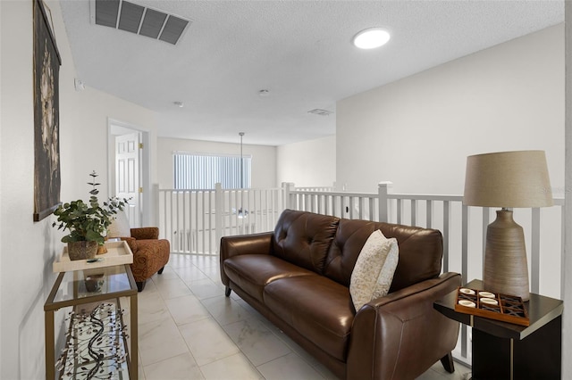 living area with visible vents, a textured ceiling, and marble finish floor