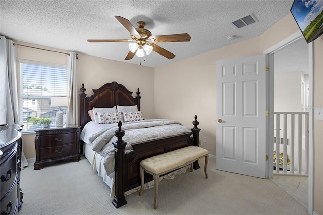 bedroom with visible vents, a ceiling fan, a textured ceiling, and light colored carpet