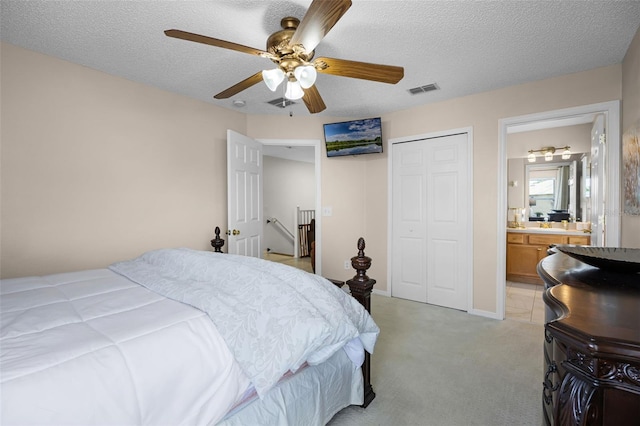 bedroom with visible vents, a closet, light carpet, ensuite bathroom, and ceiling fan