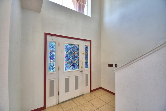 foyer featuring a high ceiling, light tile patterned flooring, and baseboards