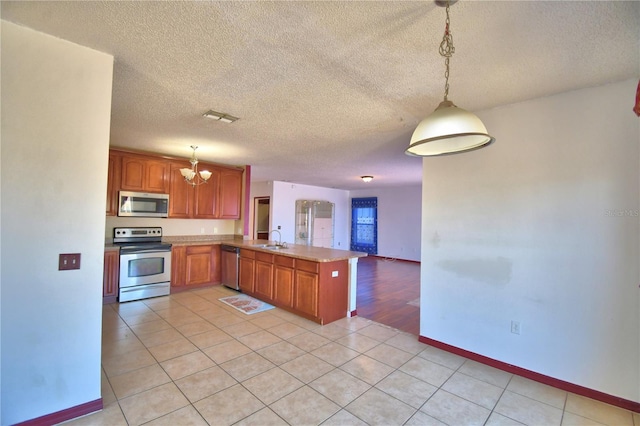 kitchen featuring a sink, a chandelier, stainless steel appliances, a peninsula, and visible vents