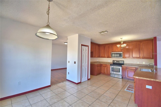 kitchen featuring stainless steel appliances, an inviting chandelier, visible vents, a sink, and baseboards