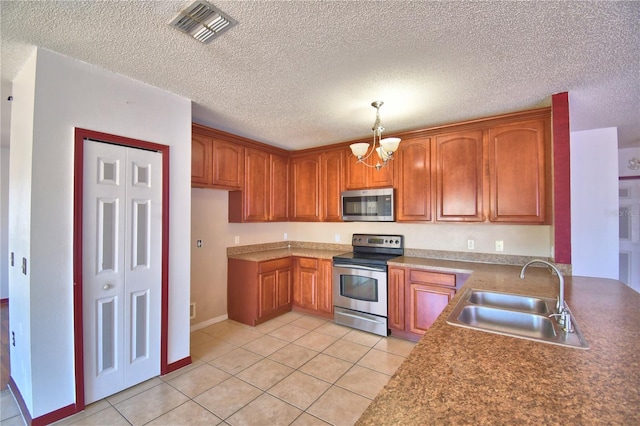 kitchen featuring a sink, brown cabinetry, light tile patterned floors, stainless steel appliances, and visible vents