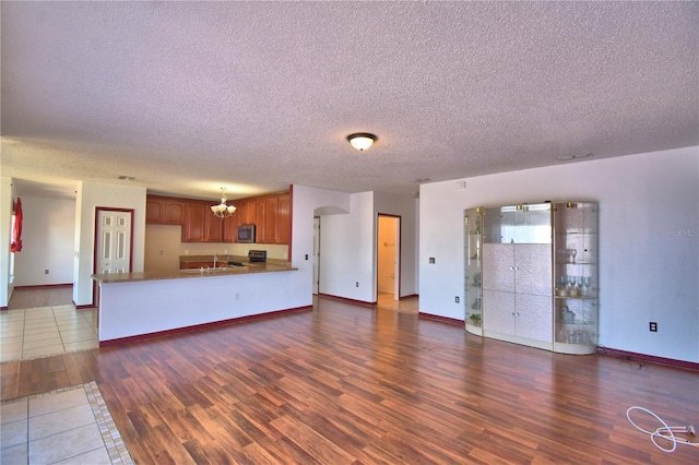 unfurnished living room with baseboards, wood finished floors, a sink, and a textured ceiling