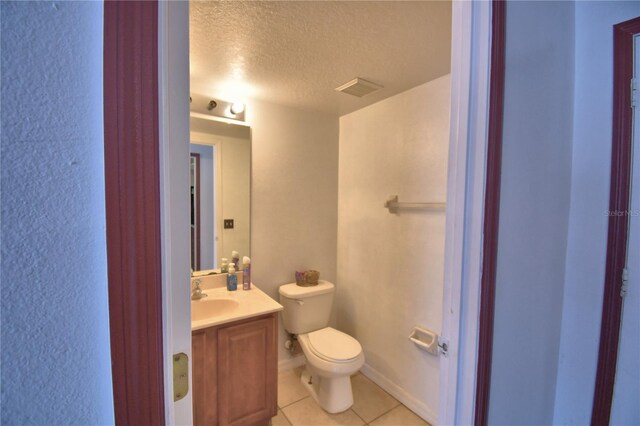 bathroom with tile patterned floors, visible vents, toilet, vanity, and a textured ceiling