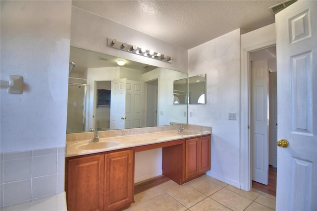 bathroom featuring a shower stall, tile patterned flooring, a sink, and a textured ceiling