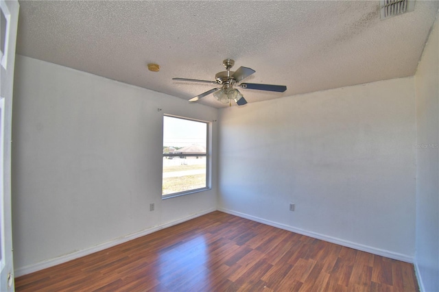 unfurnished room with baseboards, wood finished floors, visible vents, and a textured ceiling