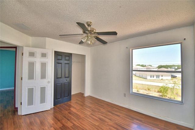 unfurnished bedroom with baseboards, wood finished floors, a textured ceiling, and a closet