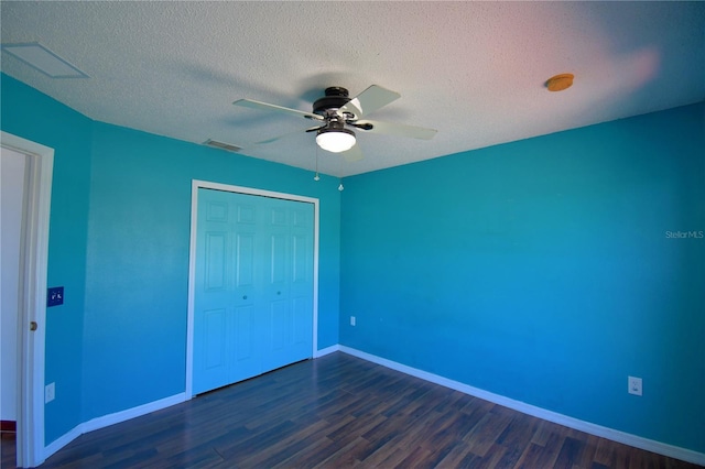 unfurnished bedroom with visible vents, a textured ceiling, dark wood-style floors, and a closet