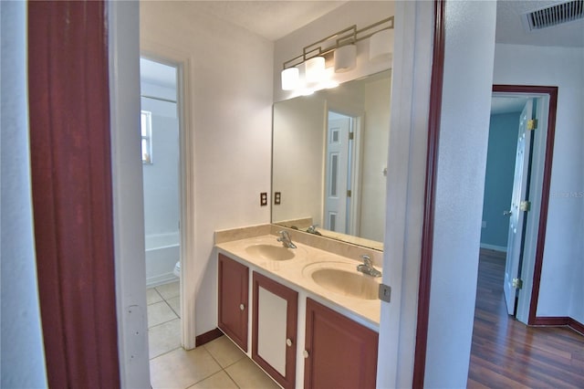 bathroom with baseboards, a sink, visible vents, and double vanity