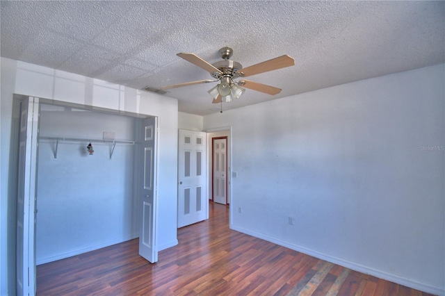 unfurnished bedroom with a textured ceiling, a closet, baseboards, dark wood-style flooring, and visible vents