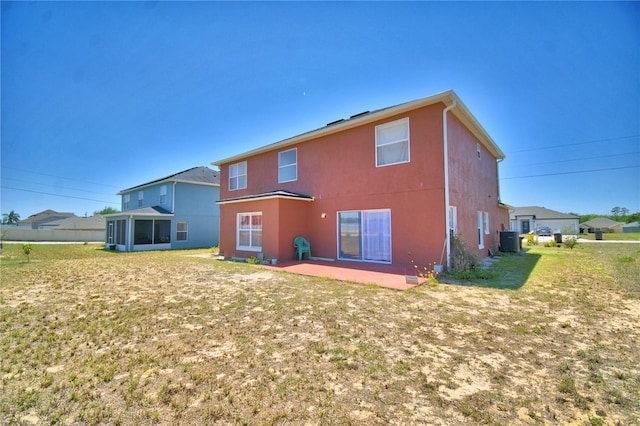 rear view of property with central AC unit, a lawn, a sunroom, a patio, and stucco siding