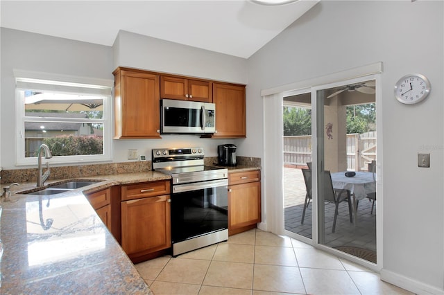 4833 Palm Tree Ct, Windermere, FL 34786 - kitchen featuring appliances with stainless steel finishes, a sink, vaulted ceiling, brown cabinets, and light tile patterned flooring