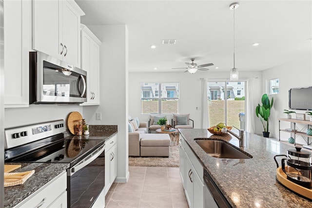 kitchen with white cabinetry, visible vents, dark stone countertops, a sink, and stainless steel appliances