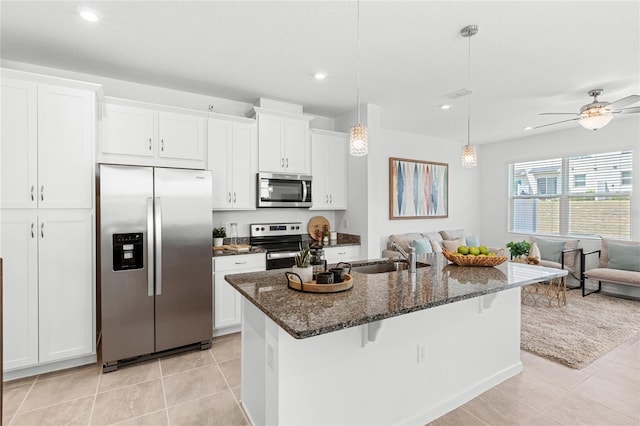 kitchen with light tile patterned floors, a sink, stainless steel appliances, open floor plan, and a breakfast bar area